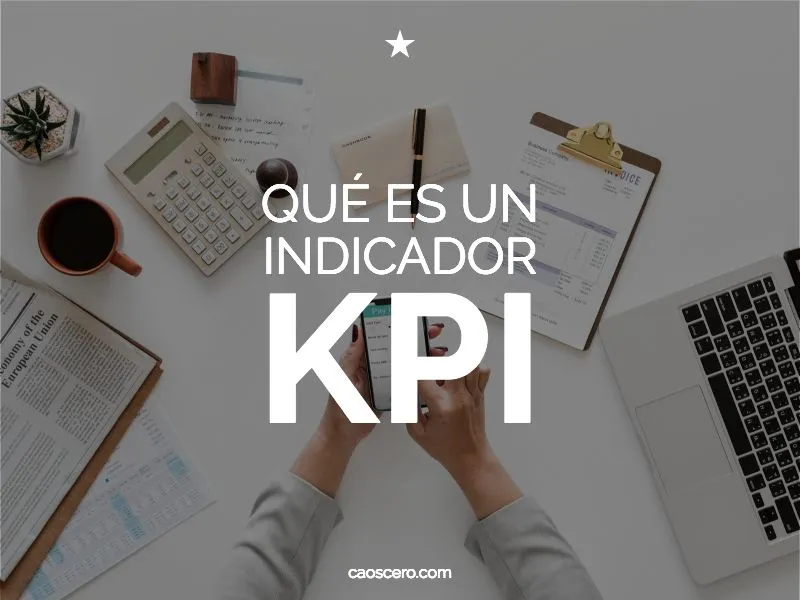 Cartel «Qué es un indicador KPI» sobre una mesa con calculadora, café, papeles y manos usando un móvil